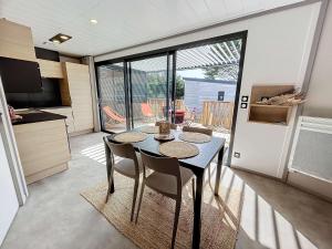 une salle à manger avec une table et des chaises dans une cuisine dans l'établissement Chalet cozy à Jullouville - 4 pers, piscine chauffée, proche plage et commerces - FR-1-361-538, à Jullouville