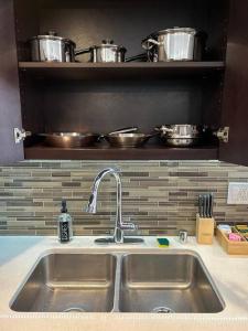 a sink in a kitchen with pots and pans on a shelf at Downtown LA - Mamba Suite - Free Indoor Parking! in Los Angeles