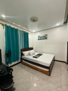 Matthew's Place Baguio city في باغيو: غرفة نوم بسرير وستارة زرقاء