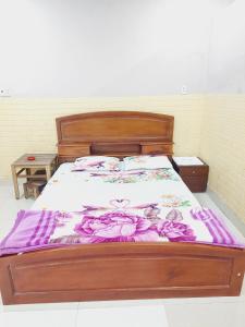 a bed with a wooden frame with flowers on it at Nhà Nghỉ Hương Giang in Xóm Cây Sanh