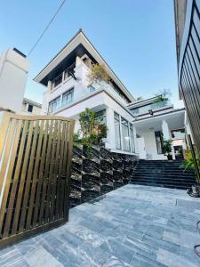 une maison blanche avec une clôture en bois et des escaliers dans l'établissement Villa FLC 7 Ngủ Hạ Long - Đẳng cấp - Phòng Karaoke riêng, à Hạ Long