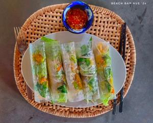 ein Teller mit Essen auf einem Korb mit einer Schüssel Sauce in der Unterkunft Beach Bar Hue Hostel in Hue