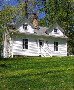 una casa blanca en la cima de un campo verde en Historic Farmhouse by Nature Preserve, en Charleston