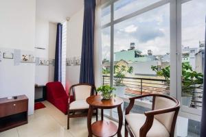 ホーチミン・シティにあるHoa Hồng Hotel Ho Chi Minh Cityのテーブルと椅子、大きな窓が備わる客室です。