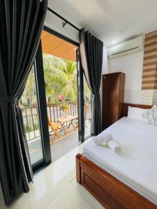 Schlafzimmer mit einem Bett und einer Glasschiebetür in der Unterkunft Cuong Thinh Homestay in Hoi An