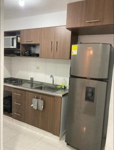 een keuken met een roestvrijstalen koelkast en houten kasten bij Increible apartamento en vup in Valledupar