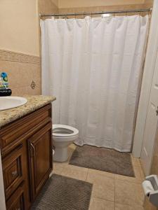 a bathroom with a white shower curtain and a toilet at Sarah's Haven in Nassau