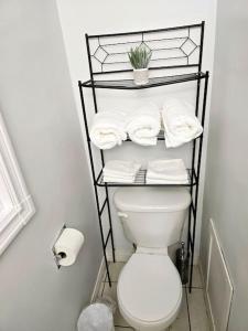 een badkamer met een toilet en een plank met handdoeken bij 3 Bedroom Home away from Home in Calgary