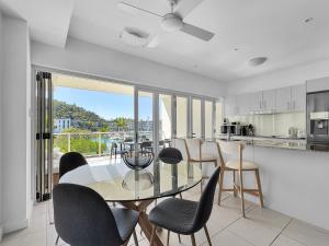 a kitchen and dining room with a glass table and chairs at Waterfront 'Beachside' Apartment - Ocean View, Central location, Pool, Wifi, King bed, Deluxe Spa Ensuite in Nelly Bay