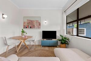 a living room with a tv and a table at Urban Chic Brisbane Retreat in Brisbane