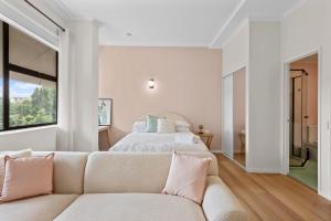 a white bedroom with a bed and a couch at Urban Chic Brisbane Retreat in Brisbane