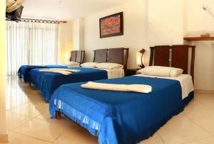 a group of three beds in a room at Hotel Puerto Bahia in San Gil