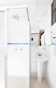 a white bathroom with a shower and a sink at Hotel Puerto Bahia in San Gil
