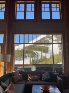 a living room with a couch and a large window at Penthouse 1 by Moonlight Basin Lodging in Big Sky