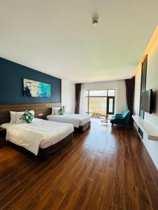 Cette chambre comprend 2 lits et une télévision à écran plat. dans l'établissement Le Palmier Ho Tram Resort, à Ho Tram