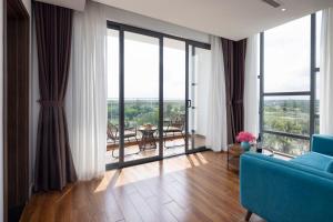 een woonkamer met een blauwe bank en grote ramen bij Le Palmier Ho Tram Resort in Ho Tram