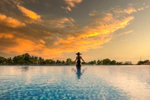 a woman in a hat standing in a body of water at Tom Hill Boutique Resort & Spa - Sea View in Phu Quoc