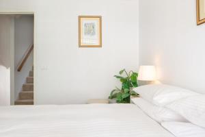 een witte slaapkamer met een bed en een lamp bij Beachfront Manly Apartment With Balcony & Parking in Sydney