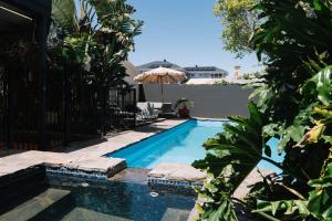 ein Pool mit Sonnenschirm und einige Pflanzen in der Unterkunft LUX Glenelg - Pool 4BD 3BA Sleeps 13 in Glenelg