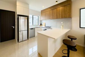 Takanini的住宿－Brand New 3Bedroom Retreat in South Auckland，厨房配有白色柜台和黑色冰箱。