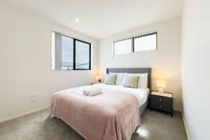 a bedroom with a large bed and two windows at Brand New 3Bedroom Retreat in South Auckland in Takanini