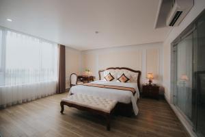 a bedroom with a bed and a bench and a window at Asean Hotel in Hải Dương