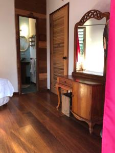 1 dormitorio con espejo y tocador de madera en Les pieds dans l’eau à huahine. Maison climatisée en Parea