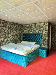 Una cama azul en una habitación con una pared de piedra. en Royal Guest House, en Skardu