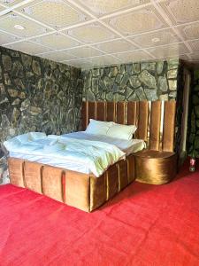 Bett in einem Zimmer mit einer Steinmauer in der Unterkunft Royal Guest House in Skardu