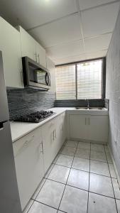 a white kitchen with a sink and a stove at Apartamento dos habitaciones in Mexicanos