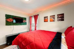 - une chambre avec un lit rouge et quelques photos sur le mur dans l'établissement Rose’s Lair in Atlanta(ATL) Near Downtown/Midtown/MARTA/Hartsfield-Jackson Airport, à Atlanta