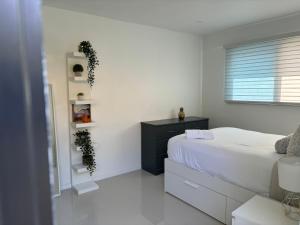 a white bedroom with a bed and a window at Comfy studio in Dania Beach