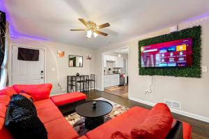 a living room with a red couch and a tv at Rose’s Lair in Atlanta(ATL) Near Downtown/Midtown/MARTA/Hartsfield-Jackson Airport in Atlanta