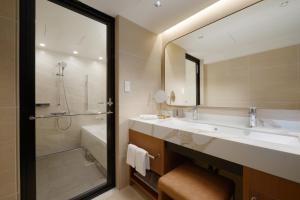 a bathroom with a sink and a tub and a mirror at Toba International Hotel in Toba