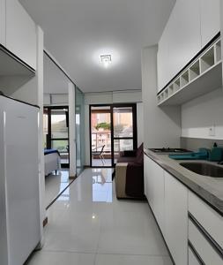 a kitchen with a sink and a living room at H.E 301 · Lindo Apt com Varanda - Caminho das árvores in Salvador
