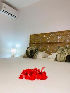 a red flower laying on a bed with a bed at Fare Orahana Moorea in Afareaitu