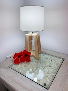 a table with a lamp and a red flower on it at Fare Orahana Moorea in Afareaitu