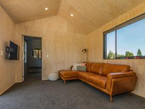 a brown leather couch in a room with a window at Sno Ruapehu - Horopito Holiday Home in Raetihi