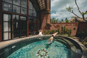 a dog is sitting next to a swimming pool at Sanctuary Villas in Ubud