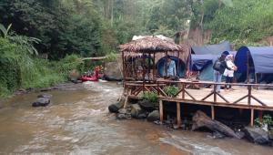 eine Gruppe von Menschen, die auf einer Brücke über einen Fluss stehen in der Unterkunft Camping Pines singkur reverside in Bandung