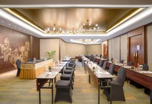 uma sala de jantar com mesas longas e cadeiras em Hotel Ciputra Semarang managed by Swiss-Belhotel International em Semarang