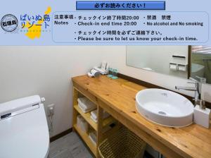 y baño con lavabo blanco y espejo. en Painushima Resort en Isla Ishigaki