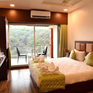 a bedroom with a large bed with a large window at Khushi Riverside Resort & Spa in Mahabaleshwar