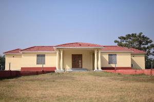 una pequeña casa amarilla con techo rojo en The Byke Niranjana, en Gaya