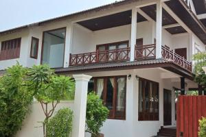 Casa blanca con balcón y árbol en MEKONG VIEW VILLE en Vientián