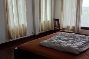 een slaapkamer met een bed, een stoel en een raam bij MEKONG VIEW VILLE in Vientiane