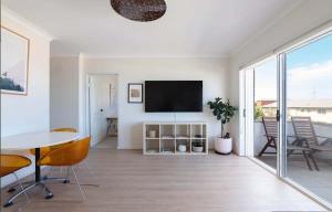 uma sala de estar com uma televisão e uma mesa e cadeiras em Stunning Maroubra Beachview Apt with Parking em Sidney