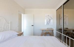 a white bedroom with a bed and a table at Stunning Maroubra Beachview Apt with Parking in Sydney