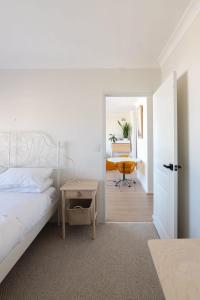 a white bedroom with a bed and a table at Stunning Maroubra Beachview Apt with Parking in Sydney