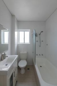 a white bathroom with a toilet and a shower at Stunning Maroubra Beachview Apt with Parking in Sydney